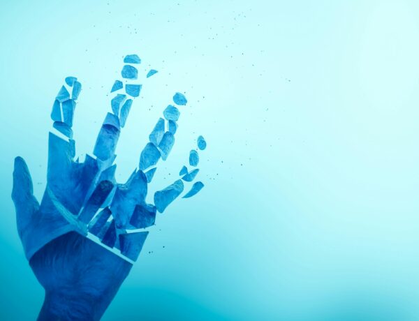 Abstract image of a blue hand breaking apart against a bright background.