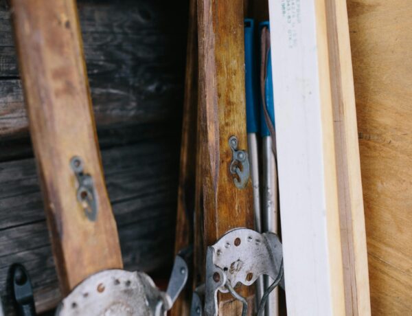 Close-up of leaning vintage wooden skis against a wooden wall with old metal bindings.